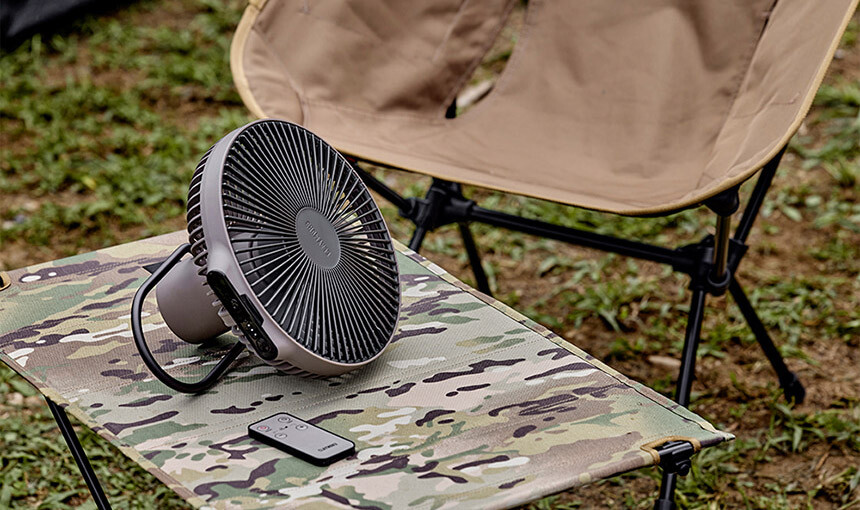 Claymore Fan V1040 warm gray model standing on its tripod in a lush green campsite setup