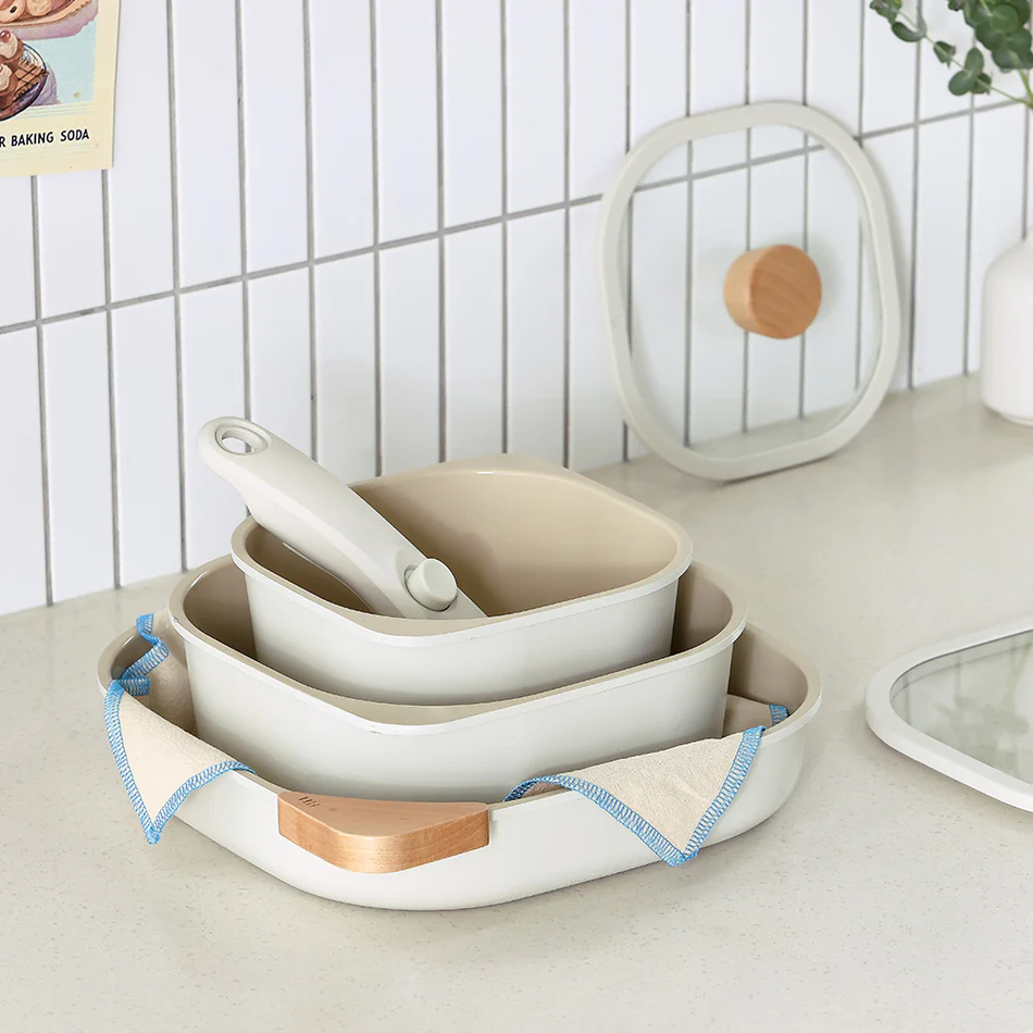 The ceramic cookware stacked neatly, showing the removable handle and space-saving nesting design
