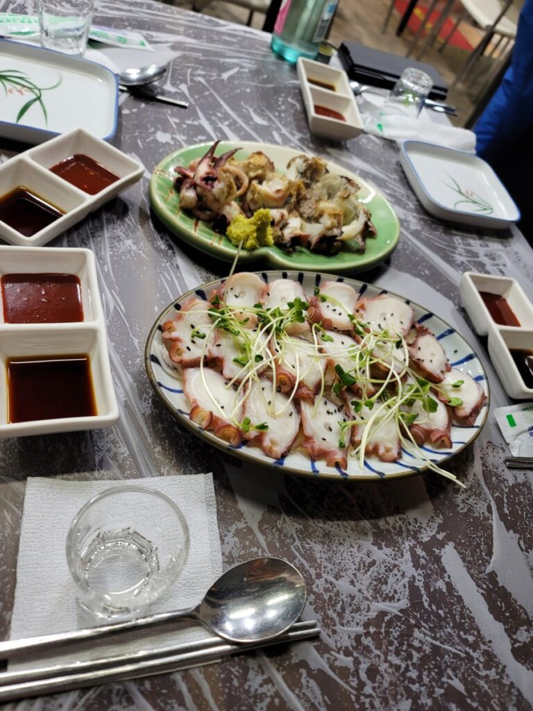 An assorted Korean seafood platter featuring tender boiled octopus, oysters, and various fresh marine delicacies.