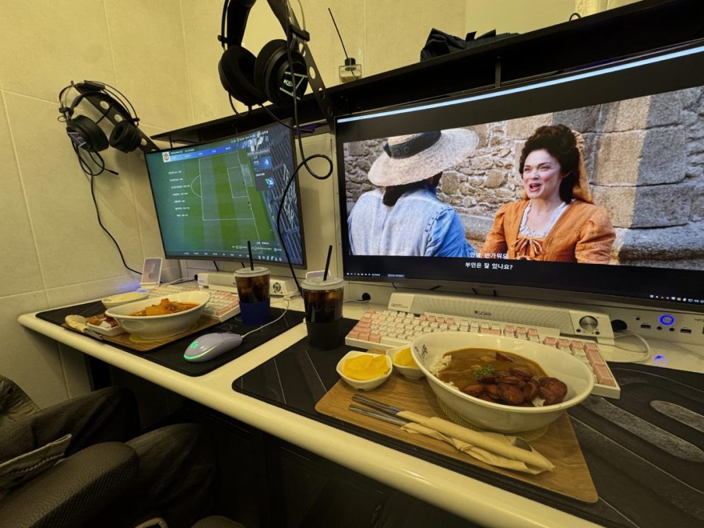 Friends enjoying games and eating food together at a Korean PC bang gaming café.