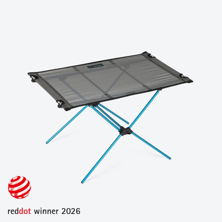 A full wide-angle shot of the Helinox Table Zero LT assembled on a wooden camp platform, showcasing its sleek design