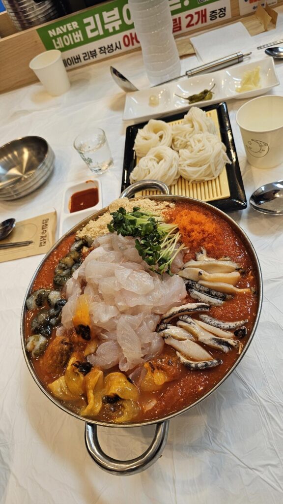 A refreshing bowl of Mulhoe, Korean cold raw fish soup with spicy ice broth and fresh vegetables, perfect for hot summer days.