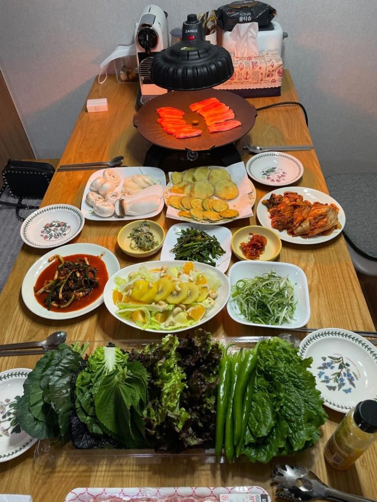 A generous Korean-style camping dinner on K-papa's outdoor table featuring authentic Korean dishes