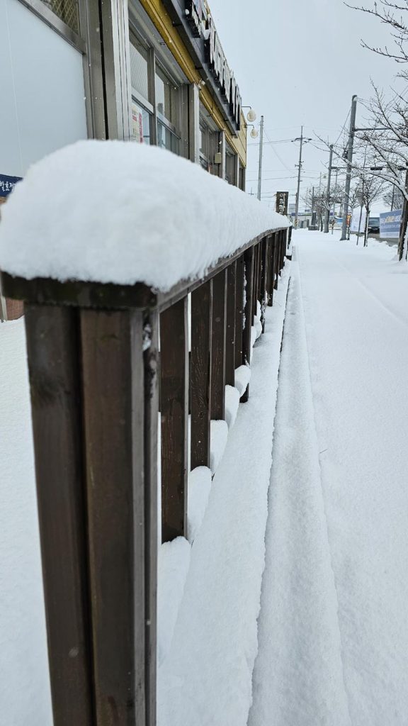 Sidewalk completely covered with heavy snowfall in a Korean residential neighborhood.