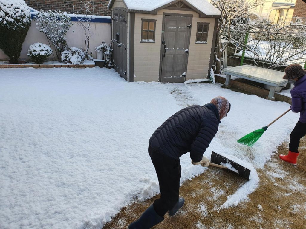 Resident shoveling heavy snow from a yard after a winter snowfall in Korea.