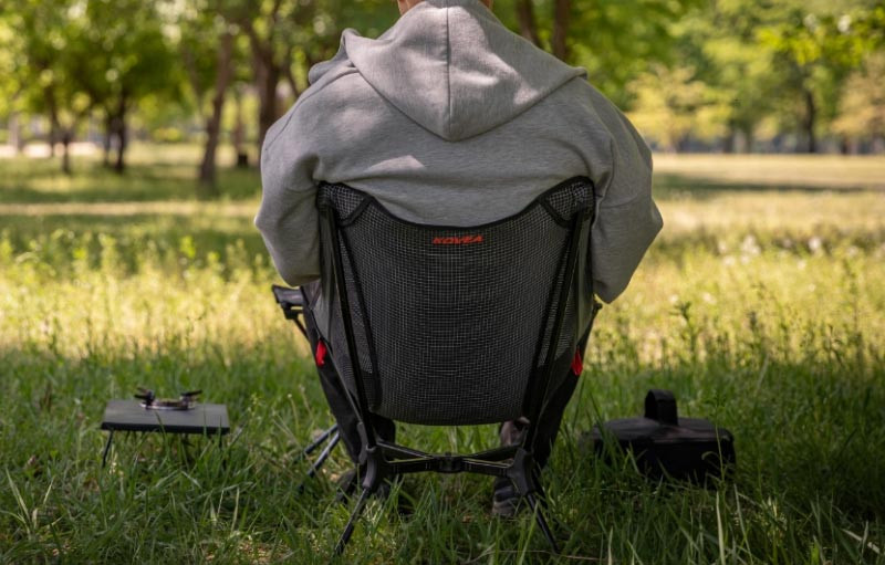 KOVEA Light Chair X review with an adult sitting comfortably in the lightweight camping chair.