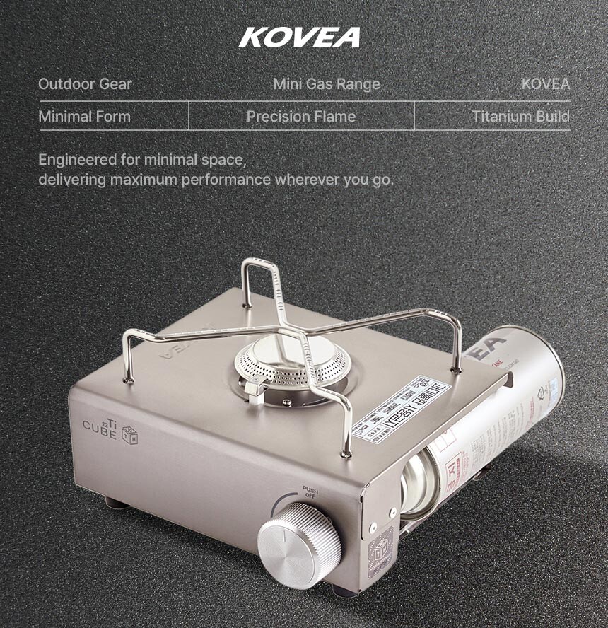 A high-resolution close-up of the Kovea Titan Cube camping burner against a clean grey background, highlighting its sleek metallic texture.