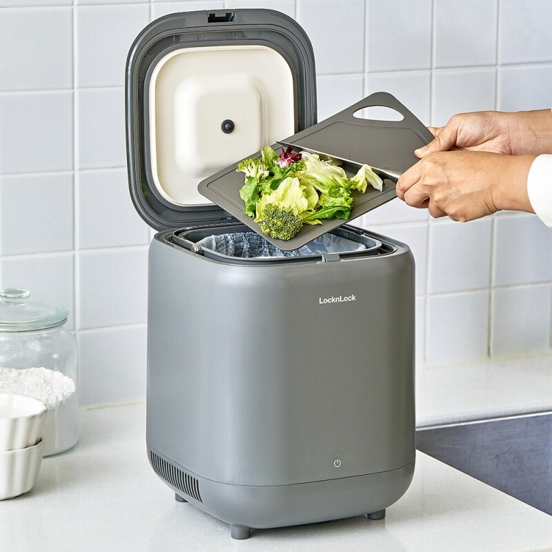 Food scraps being placed into the gray LocknLock Food Waste Refrigerator to reduce kitchen odors.