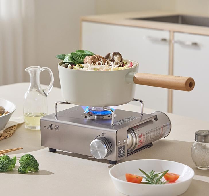 Cooking a meal on a kitchen counter using the stylish Kovea Titan Cube stove, showing its high thermal efficiency and interior-friendly design.