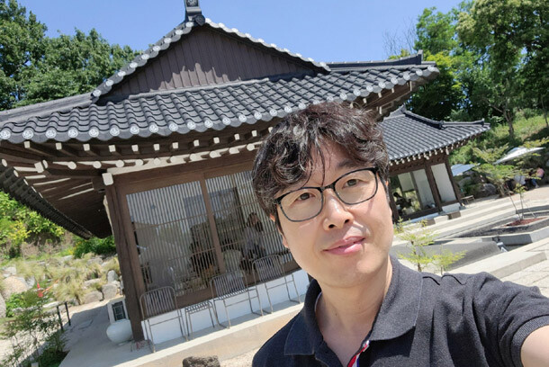 K-papa smiling in front of a traditional Korean hanok house