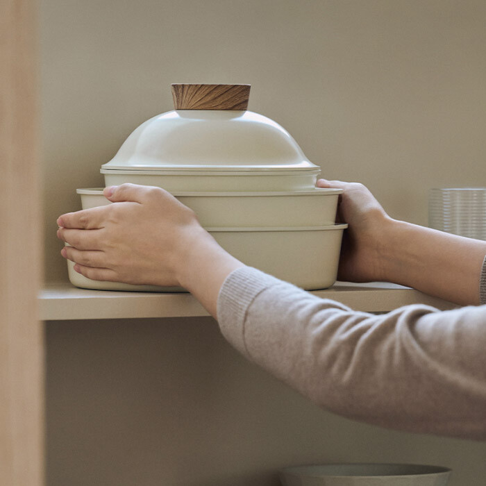 Modori pots and pans stored compactly inside a kitchen cabinet drawer, showcasing space-saving nesting design.