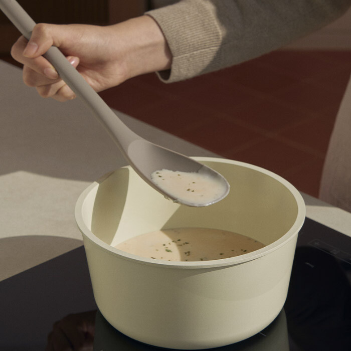 Close-up of a silicone spatula gliding smoothly across the flawless white ceramic non-stick surface of a Modori pan.