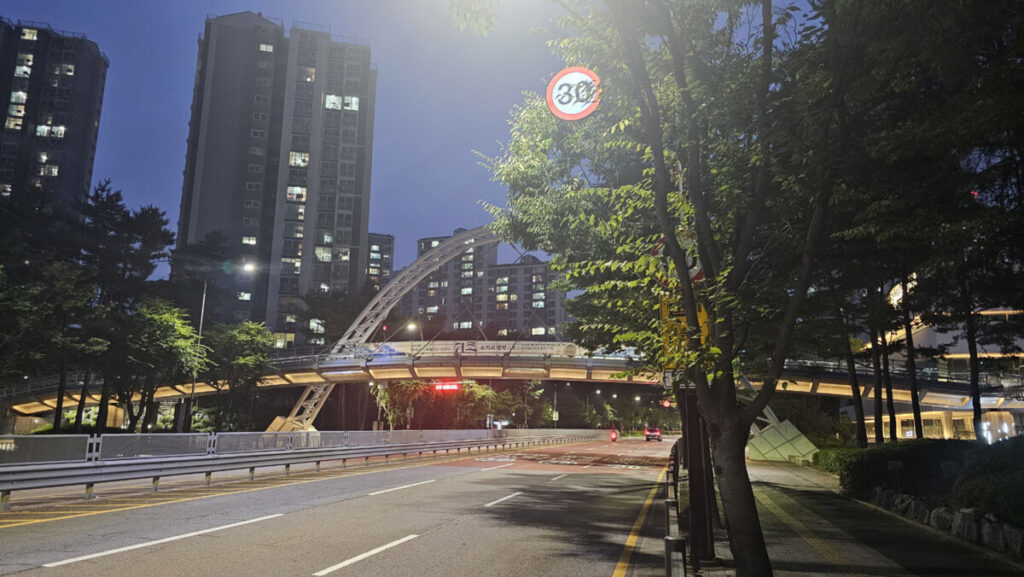 Beautiful night view of a pedestrian overpass bridge with soft architectural lighting in a Korean neighborhood.