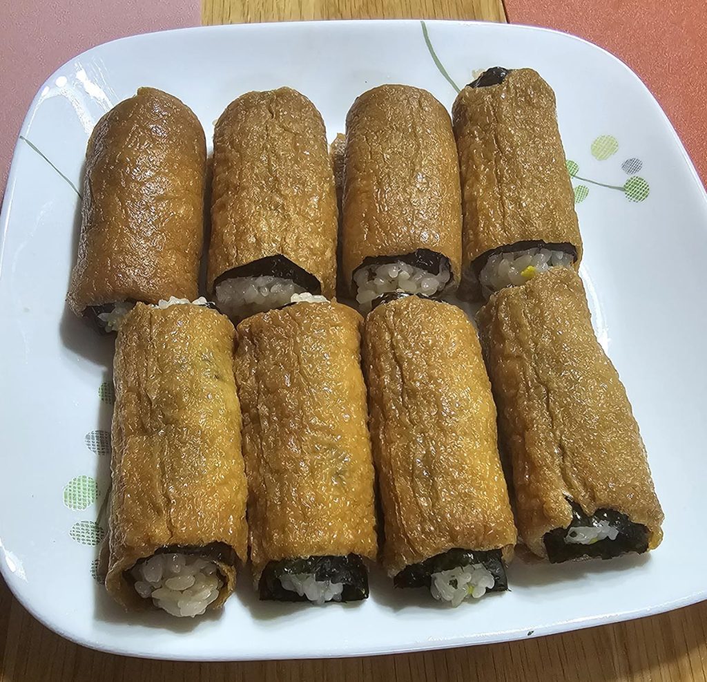 Easy homemade kimbap rolls wrapped in seasoned fried tofu pockets on a white plate