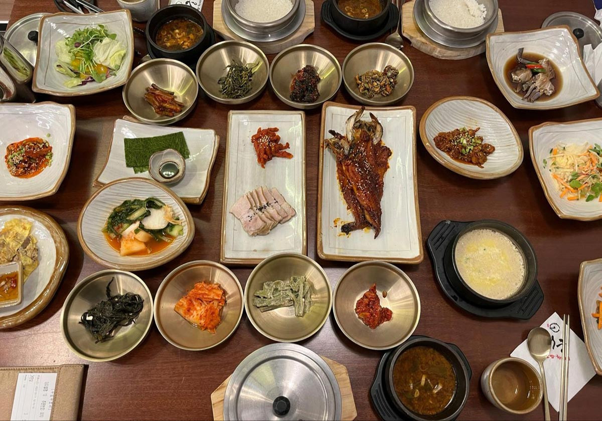 Korean banchan culture shown through a table filled with rice, soup, kimchi, and several side dishes