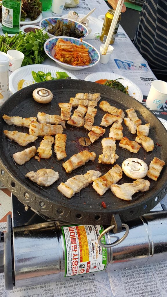 Korean samgyeopsal cut into bite-size pieces and grilled with mushrooms during an outdoor meal