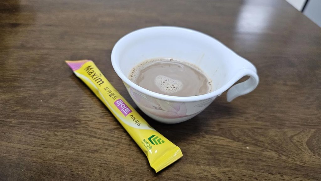 A cup of prepared Maxim Mocha Gold Light coffee with an individual coffee mix stick