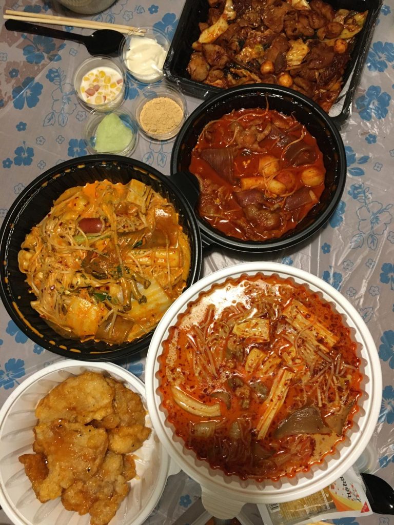 Assorted spicy Korean delivery dishes including tteokbokki, braised chicken, seafood, and fried chicken