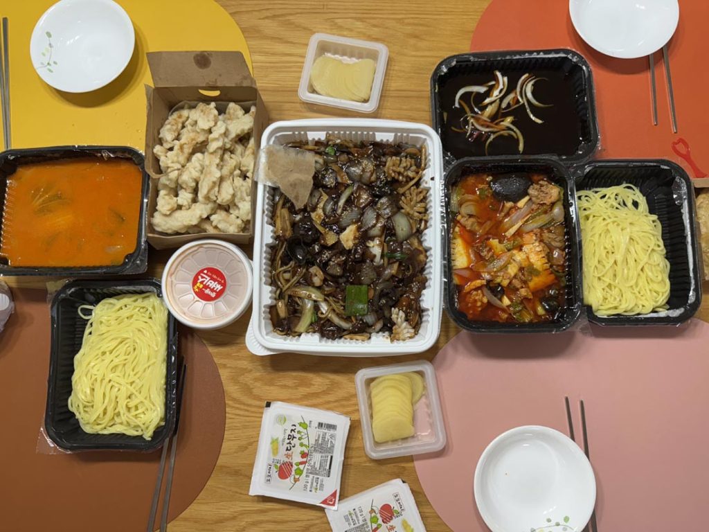 Korean Chinese delivery meal with jajangmyeon, spicy seafood noodles, tangsuyuk, and pickled radish