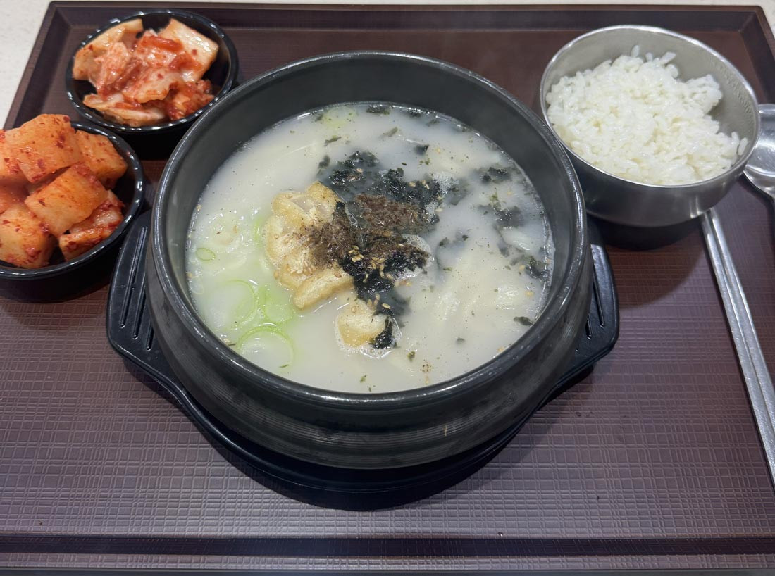 A hot Korean soup served with steamed rice, napa cabbage kimchi, and cubed radish kimchi.