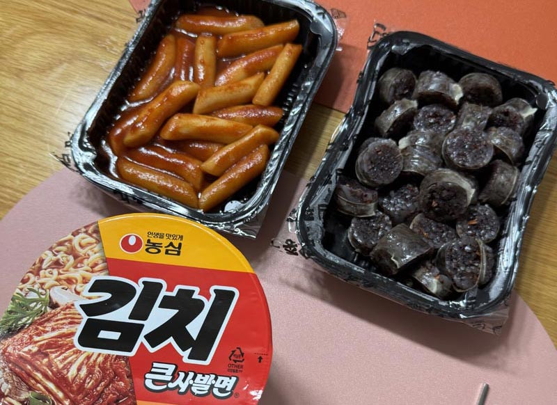 Delivered Korean tteokbokki and sliced sundae blood sausage served with a cup of kimchi noodles main image